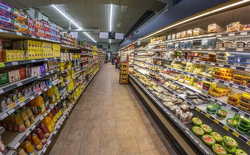 An aisle of the Intermarché supermarket, jars and bottles of preserves on the shelves to the left and the refrigerated cases of cured meat a
