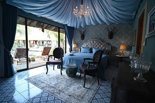 This photo depicts a luxurious bedroom with a stunning view of a pool. The room is adorned with a blue canopy bed, which is the centerpiece